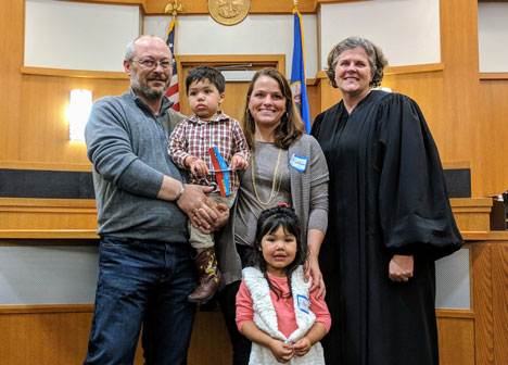 Family posing with judge in courtroom at National Adoption Day 2017 event