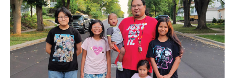 A dad standing in a neighborhood with five kids ranging from toddler to 10 years old.