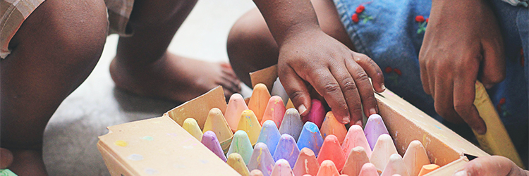 child touching a box of colorful chalk