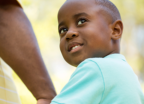 Young smiling boy holding an adult's hand