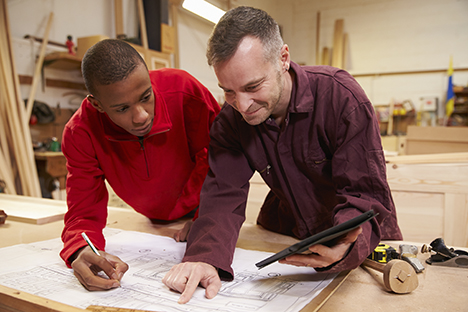 Carpenter and apprentice looking at plans