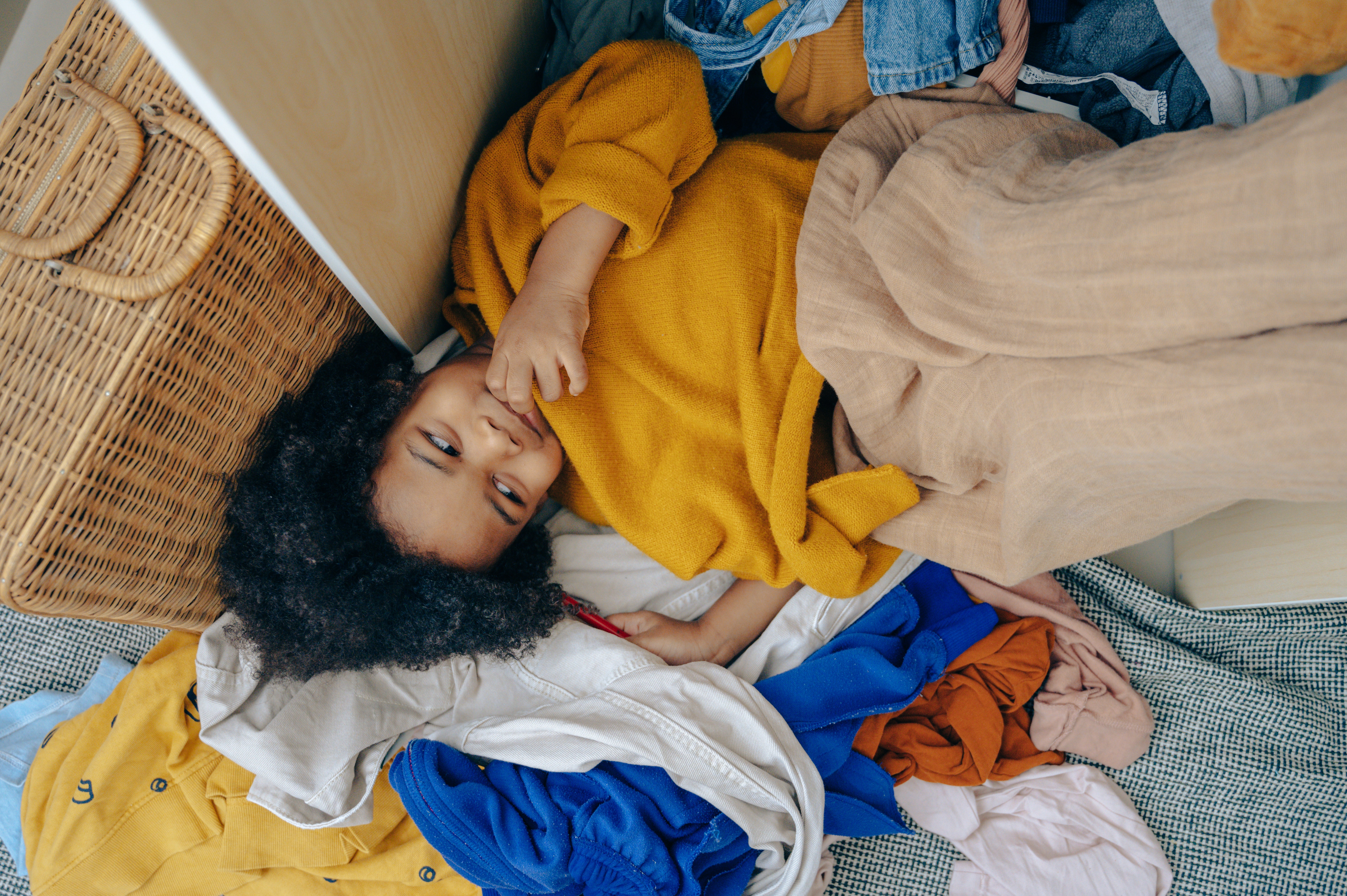 Kid laying on clothes on the floor