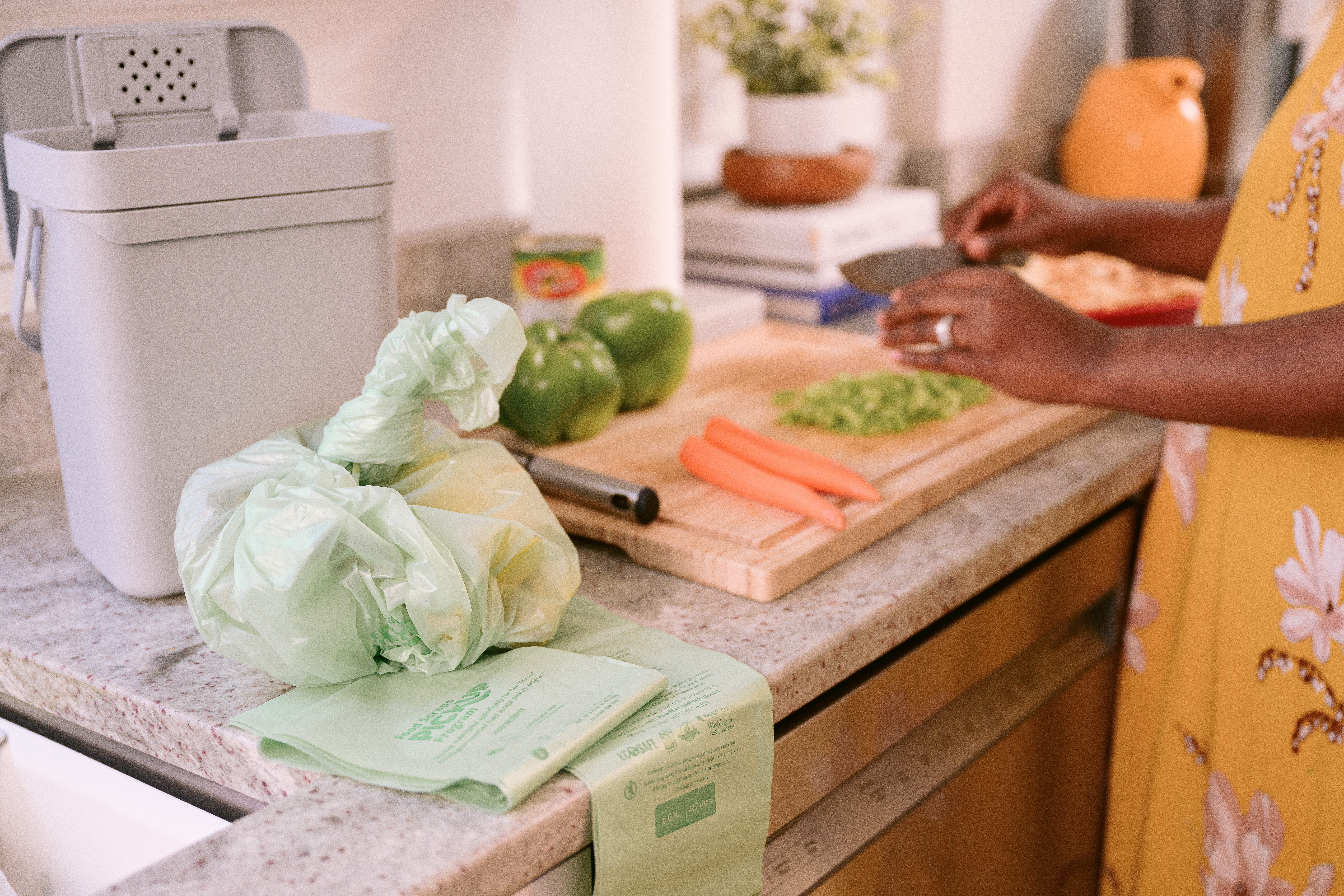 Bag of food scraps sitting on counter as someone prepares to cut food