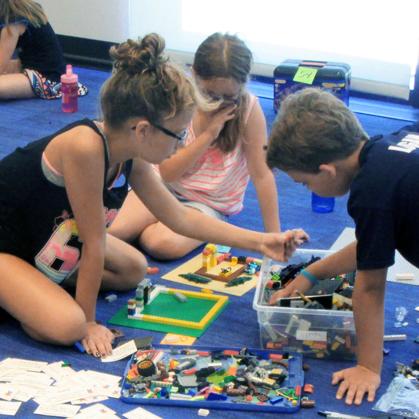 Three children play with Lego on the floor. Three children play with Lego on the floor.