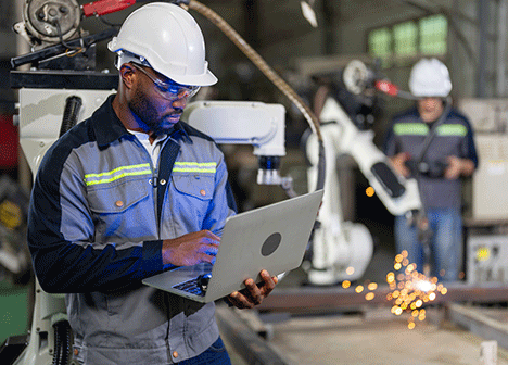 Engineer looking at computer in manufacturing plant