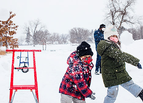 two children throwing snowballs toward the camera