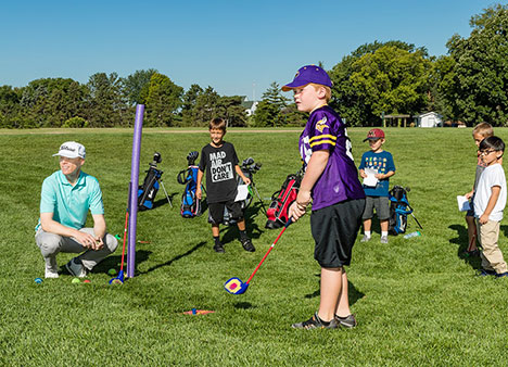 Keller instructor Jon Reigstad leading a golf lesson for five boys