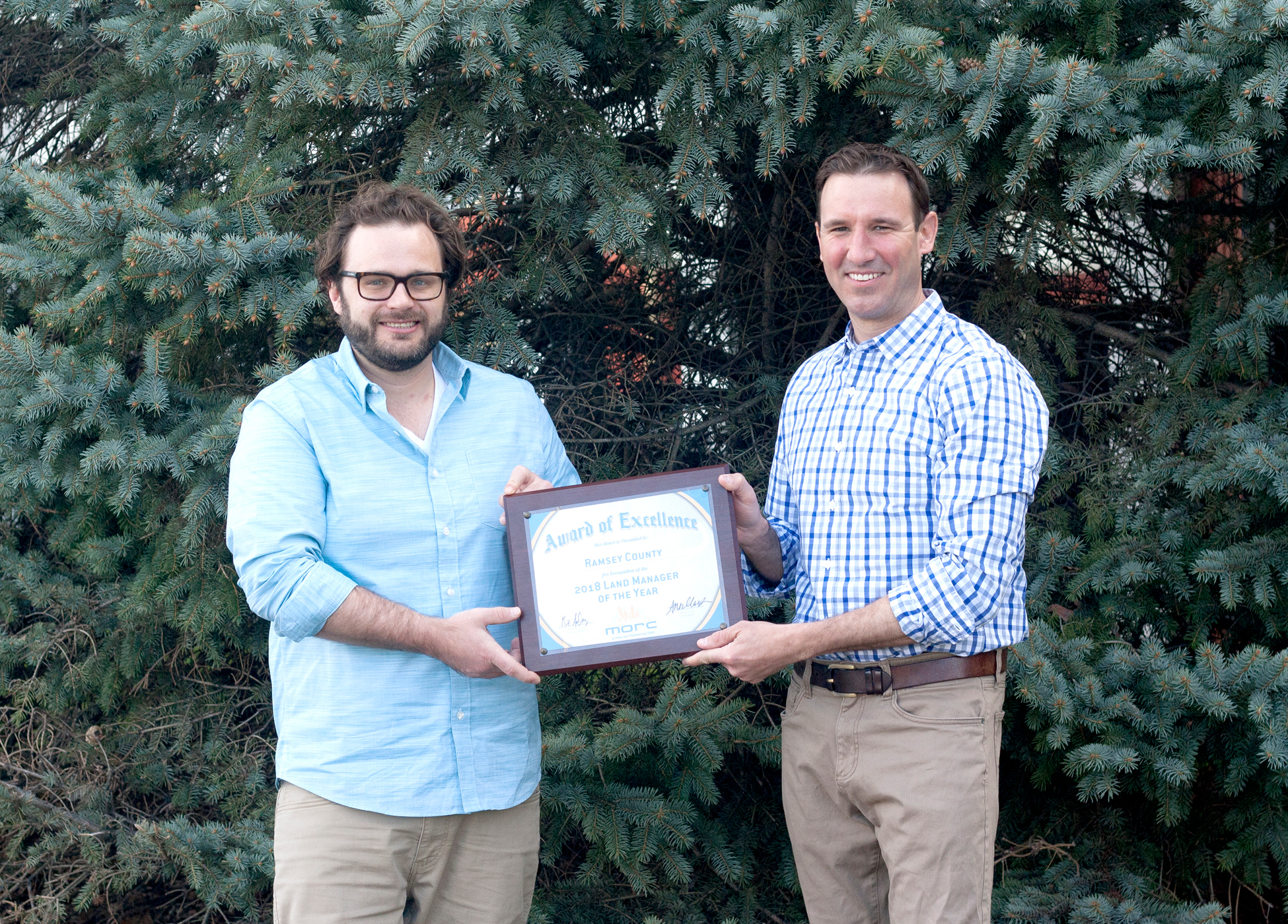 Two Parks & Recreation staff members displaying the award plaque.