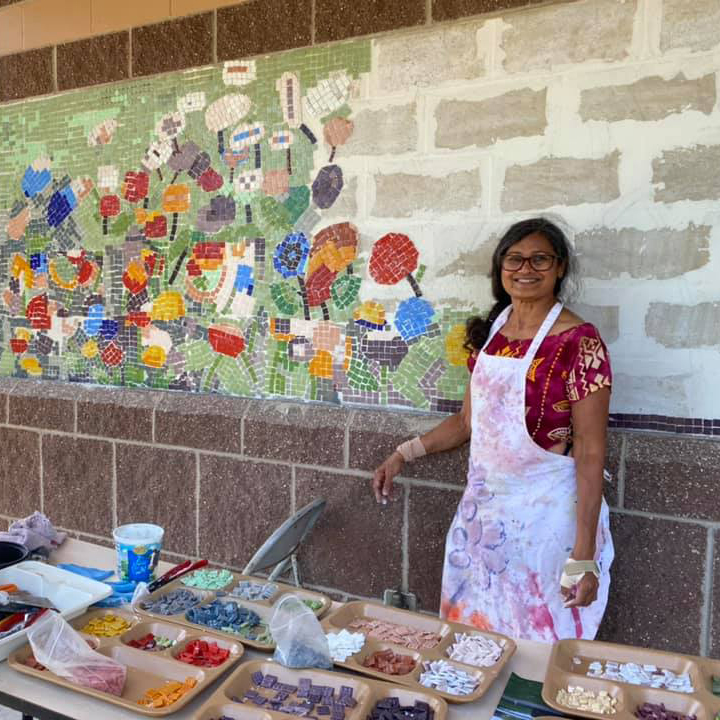 Artist Shakun Maheshwari smiling next to her colorful mosaic artwork at the picnic shelter pillars at McCarrons County Park.