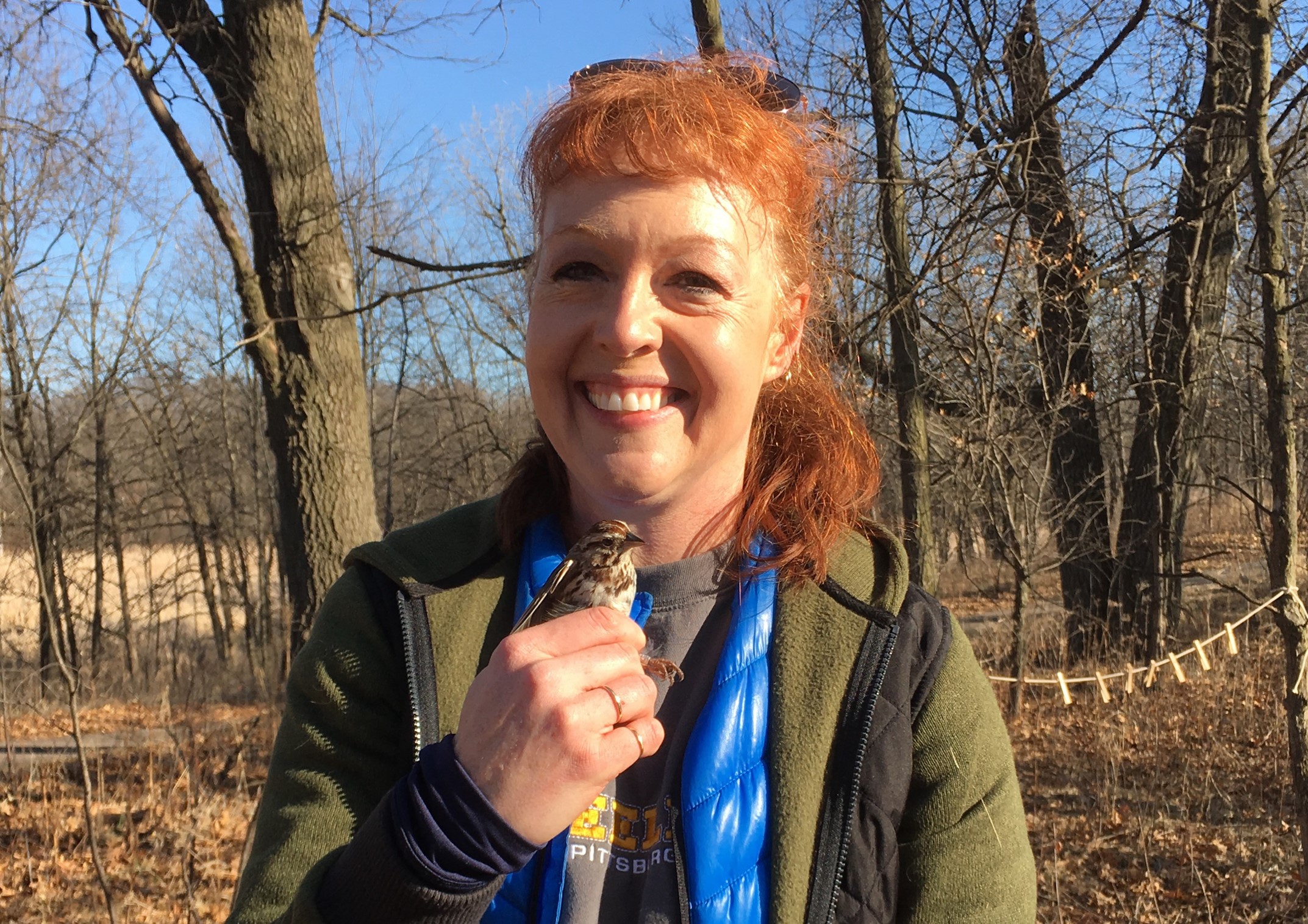 Amber Burnette smiling while holding a kestral bird in hand.