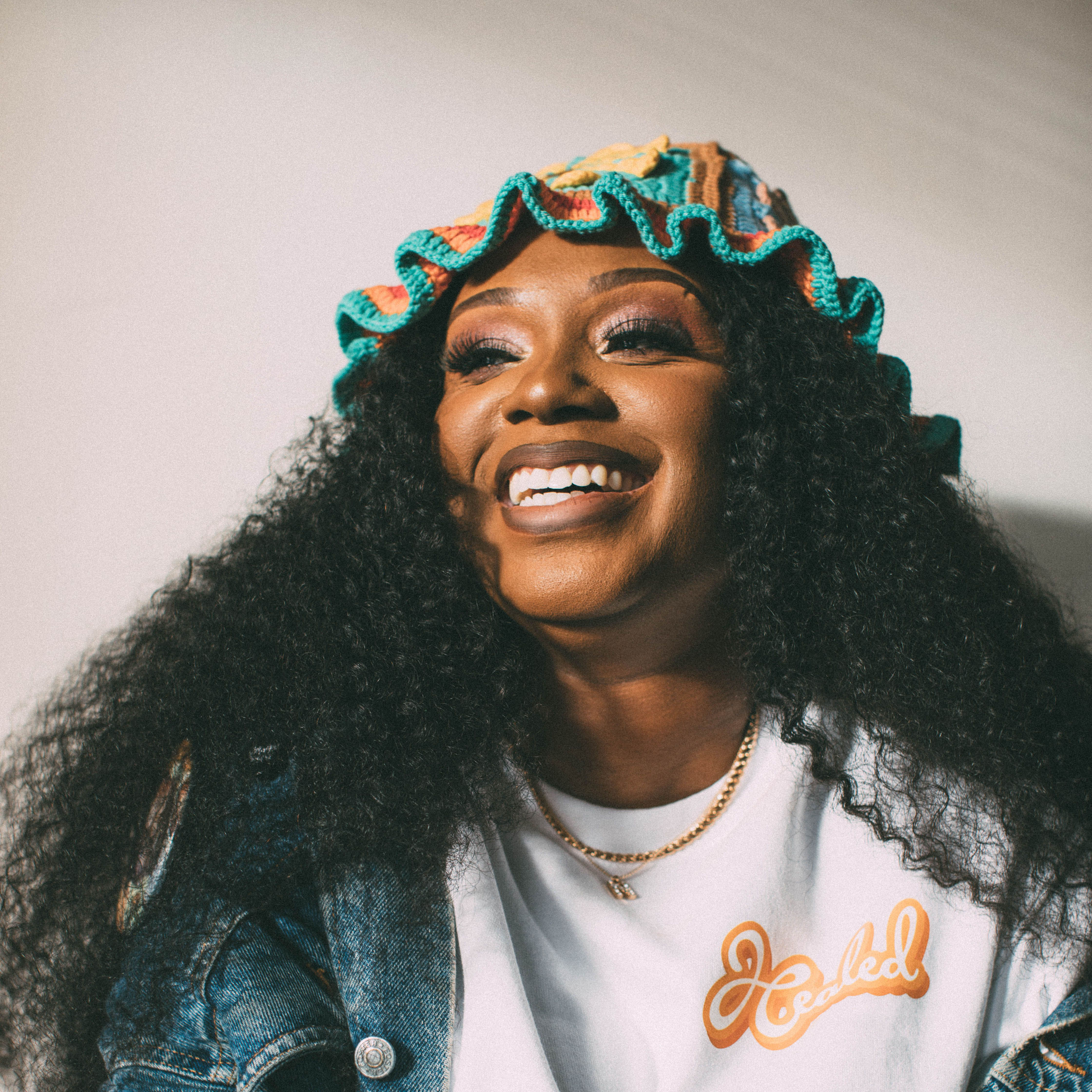 Ramsey county parks and recreation artist organizer, Nakara Forjé White smiling with a colorful hat and jean jacket.
