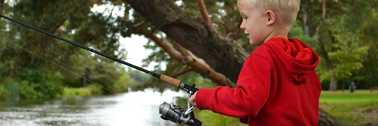 Boy in red sweater fishing with a rod near the lake at Battle Creek Regional Park.