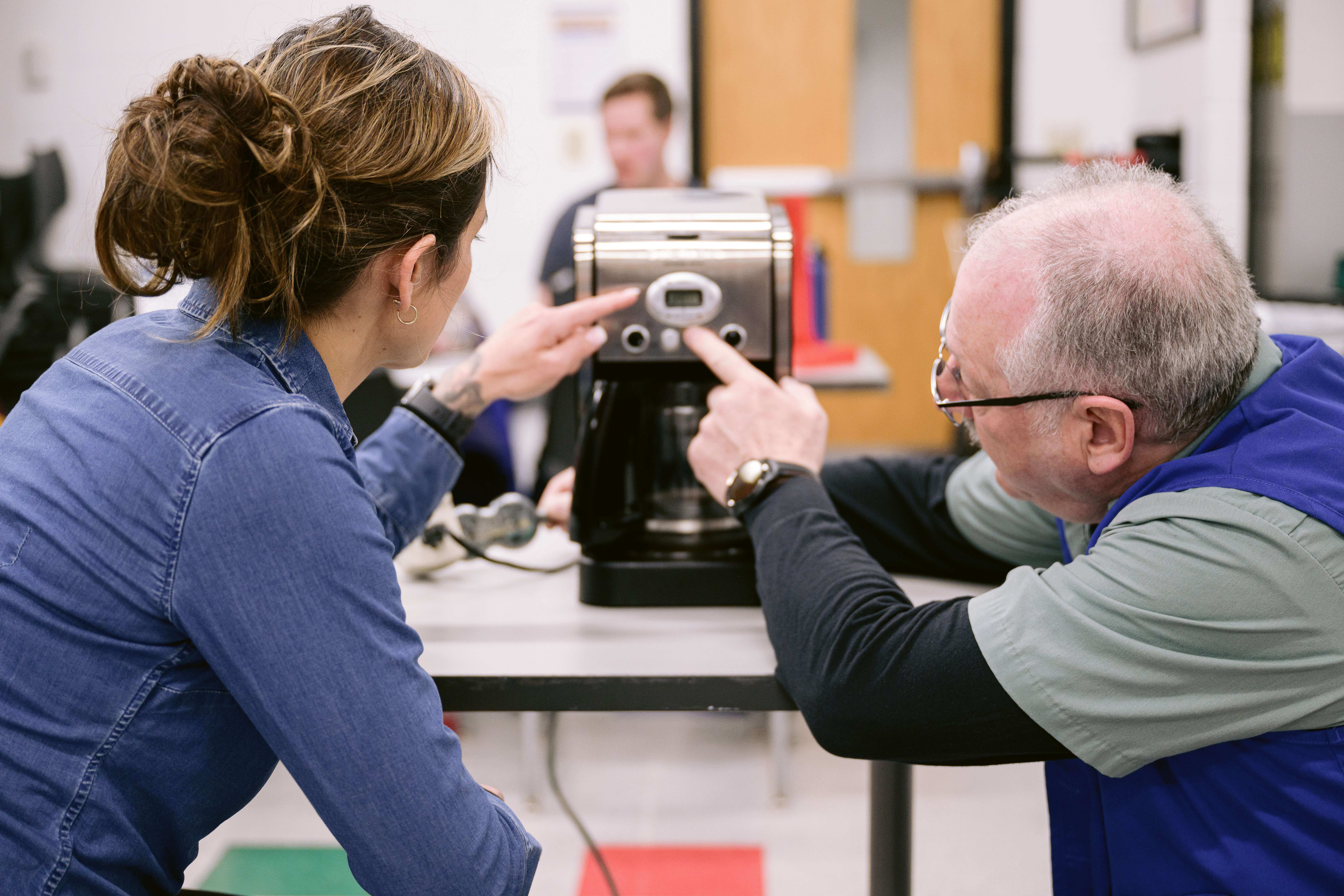Volunteer and participant fixing a coffee maker together