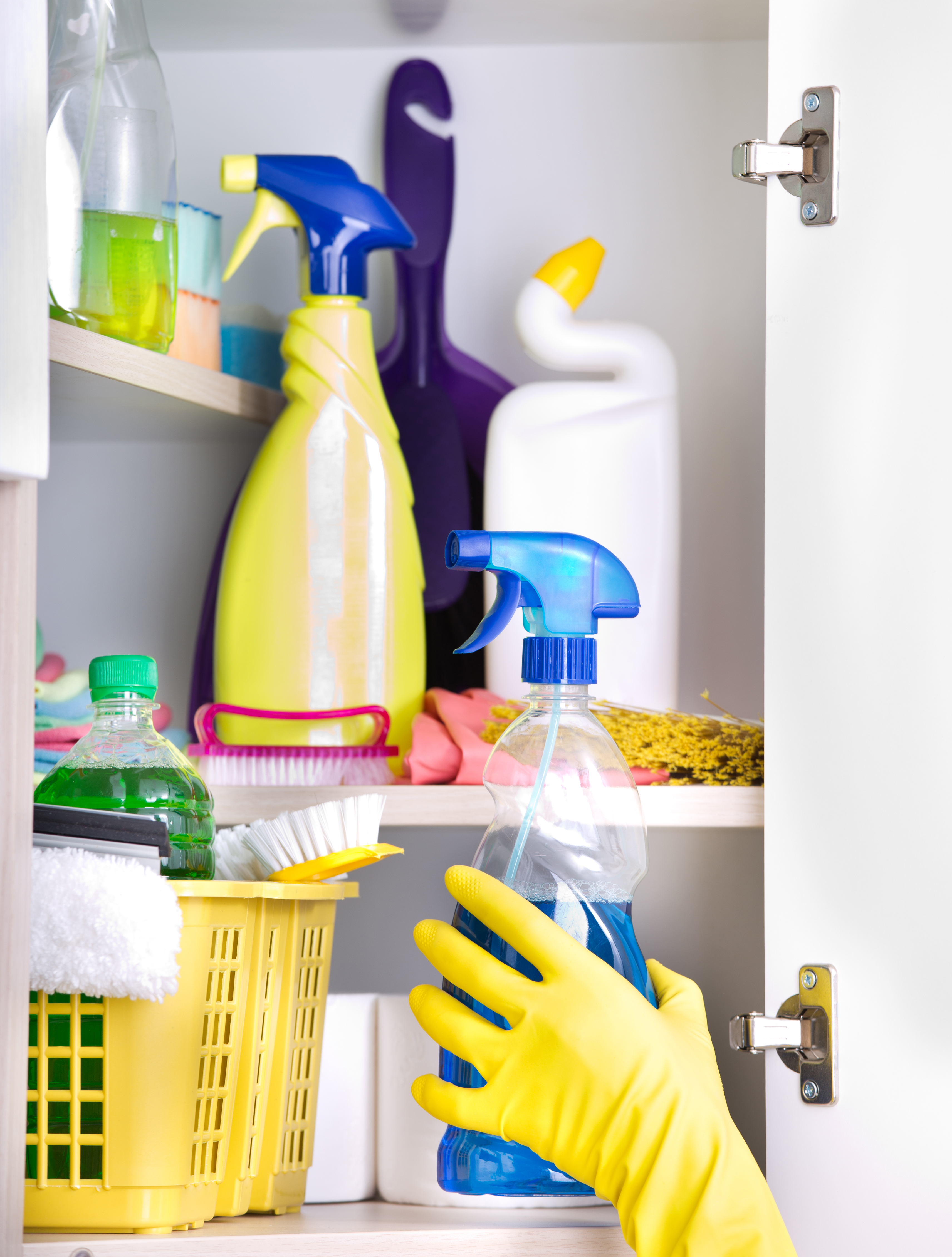Cleaning products on a shelf with a hand covered in a rubber glove grabbing one