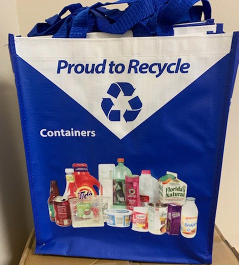 reusable tote bag with the words "Proud to recycle" across the top and images of items that can be recycled on the bag.