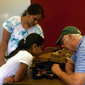 Volunteer works with Fix-It Clinic attendees to repair item Volunteer works with Fix-It Clinic attendees to repair item