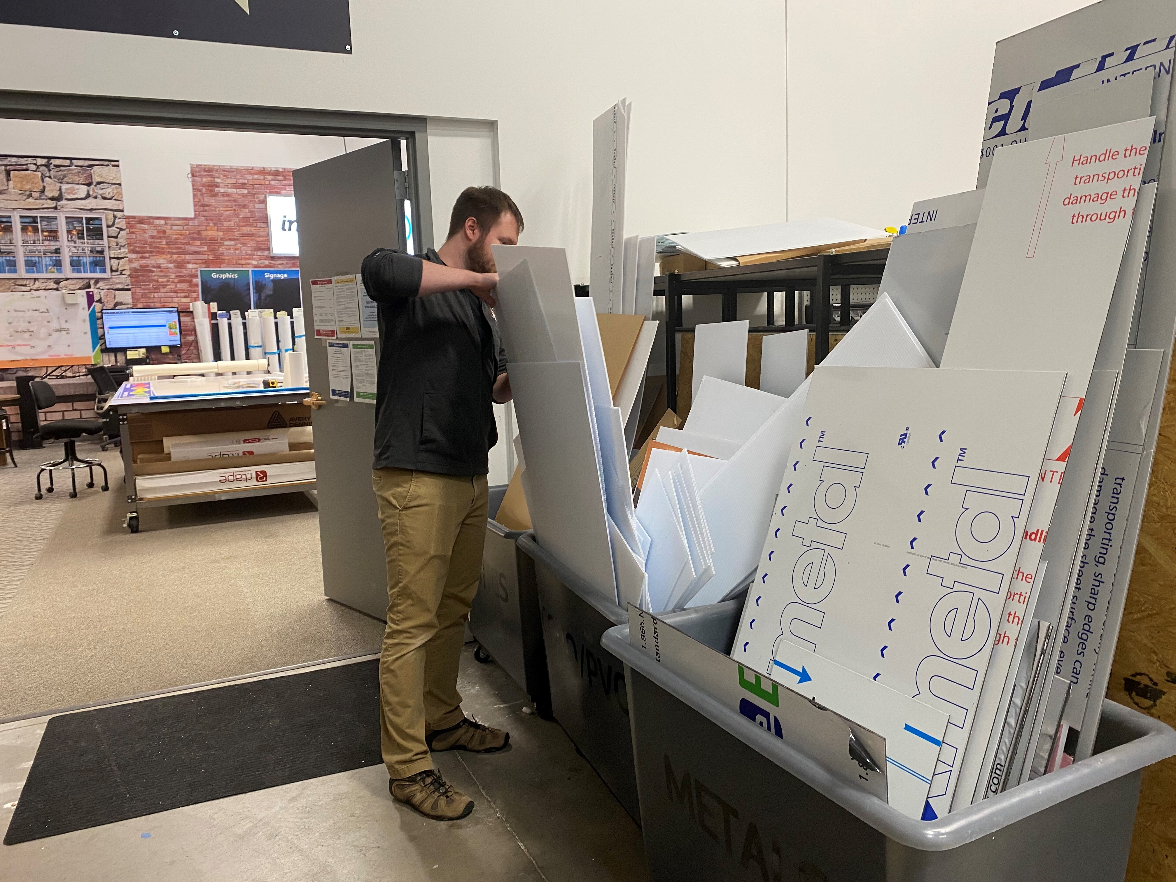 Man placing signage in recycling bins at Image360 Woodbury