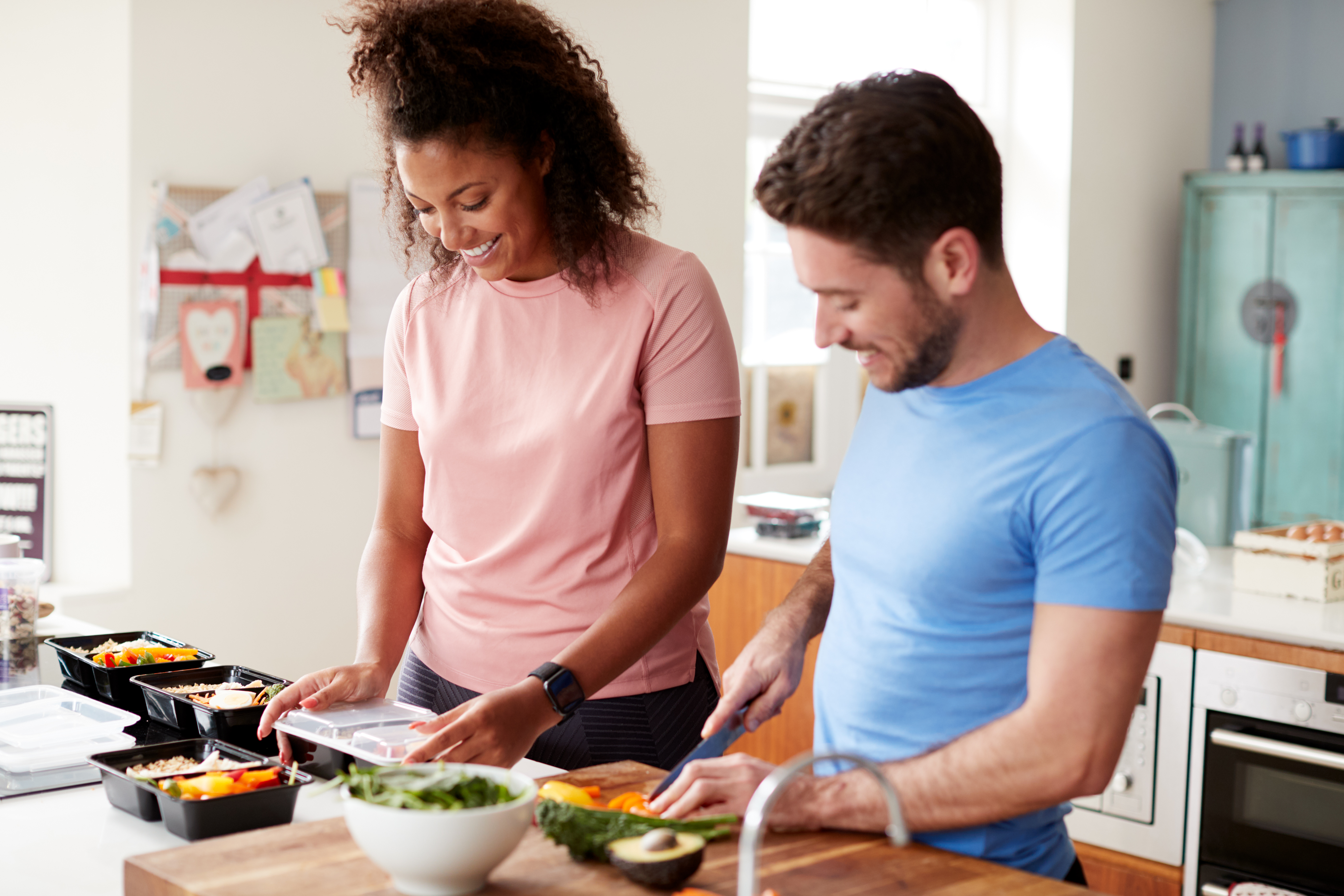 Man and woman smiling while preparing meals