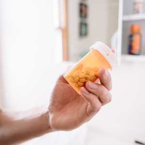 a hand holds a bottle of prescription medicine.