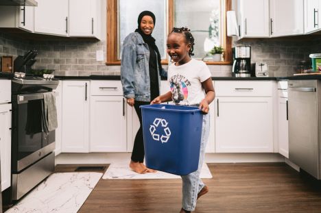 Mother and daughter with blue recycling bin