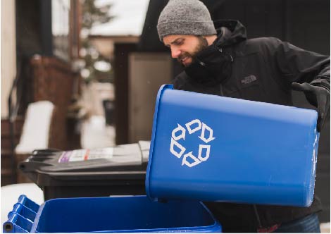 Man pouring items into recycling cart outside in winter