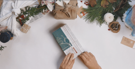 Hands wrapping a gift in recyclable newspaper