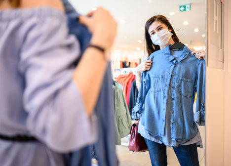 Young girl holding up a denim shirt in the store mirror