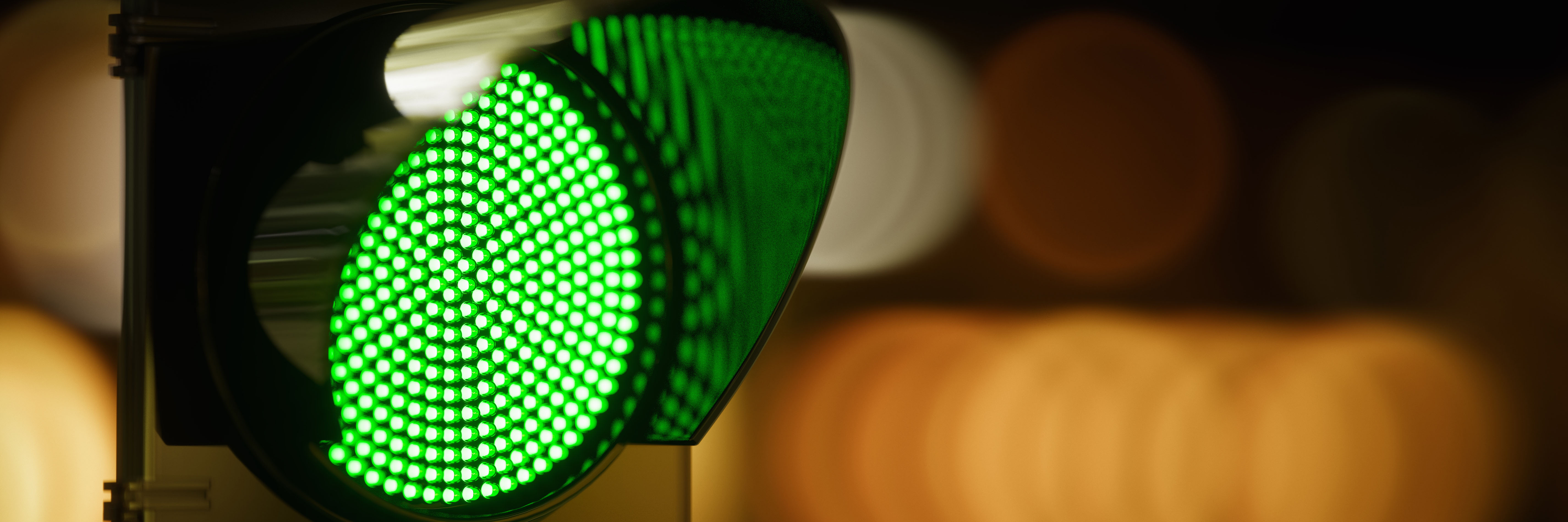 A traffic signal with an illuminated green light at night.