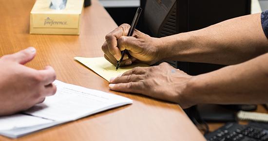 Volunteer Information desk attendant writing down notes for a resident