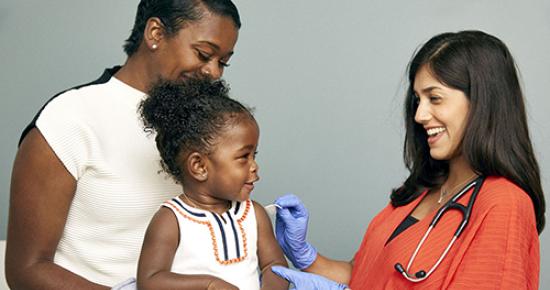 Young black girl is sitting on her mother's lap while being prepped for a vaccine from a care provider  by SELF Magazine and the American Association of Pediatrics