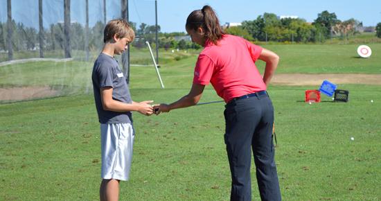 Golf instructor giving a lesson to a teenage boy