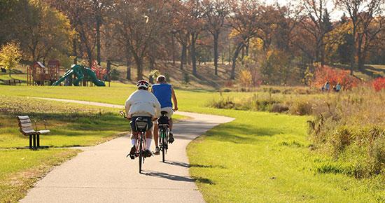 Two people biking at a park during the fall season.
