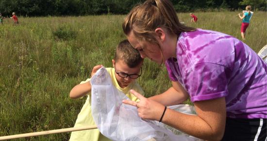 Volunteer and child in a field at Tamarack Nature Center