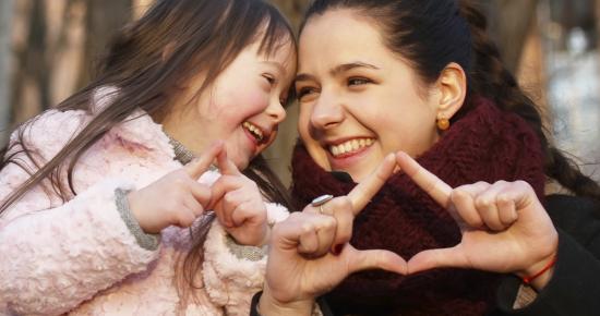 Older and younger sister smiling at each other