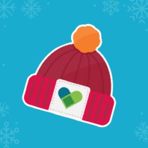 Red winter hat with orange pom pom on top and bandaid heart on the front in front of a blue background with snowflakes.
